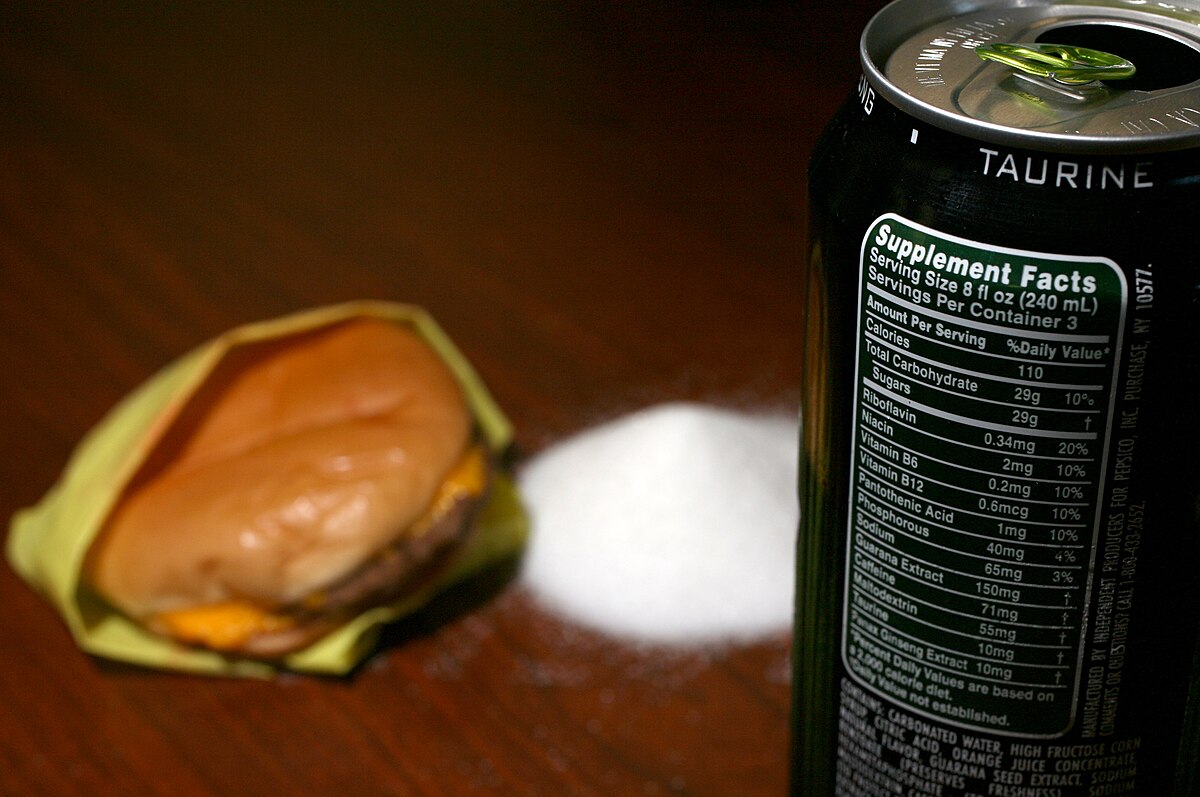 An image showing a burger and a can of energy drink with the supplement facts writing on it, including the word “TAURINE”.